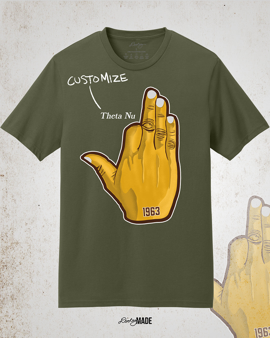 Image showing the front of a customizable Iota Phi Theta shirt with a large gold, brown, and white "Ow-Ow" hand sign on the front with "1963." Above there is a line leading from the word "customize" to customizable text. Shirts are on a textured white background.