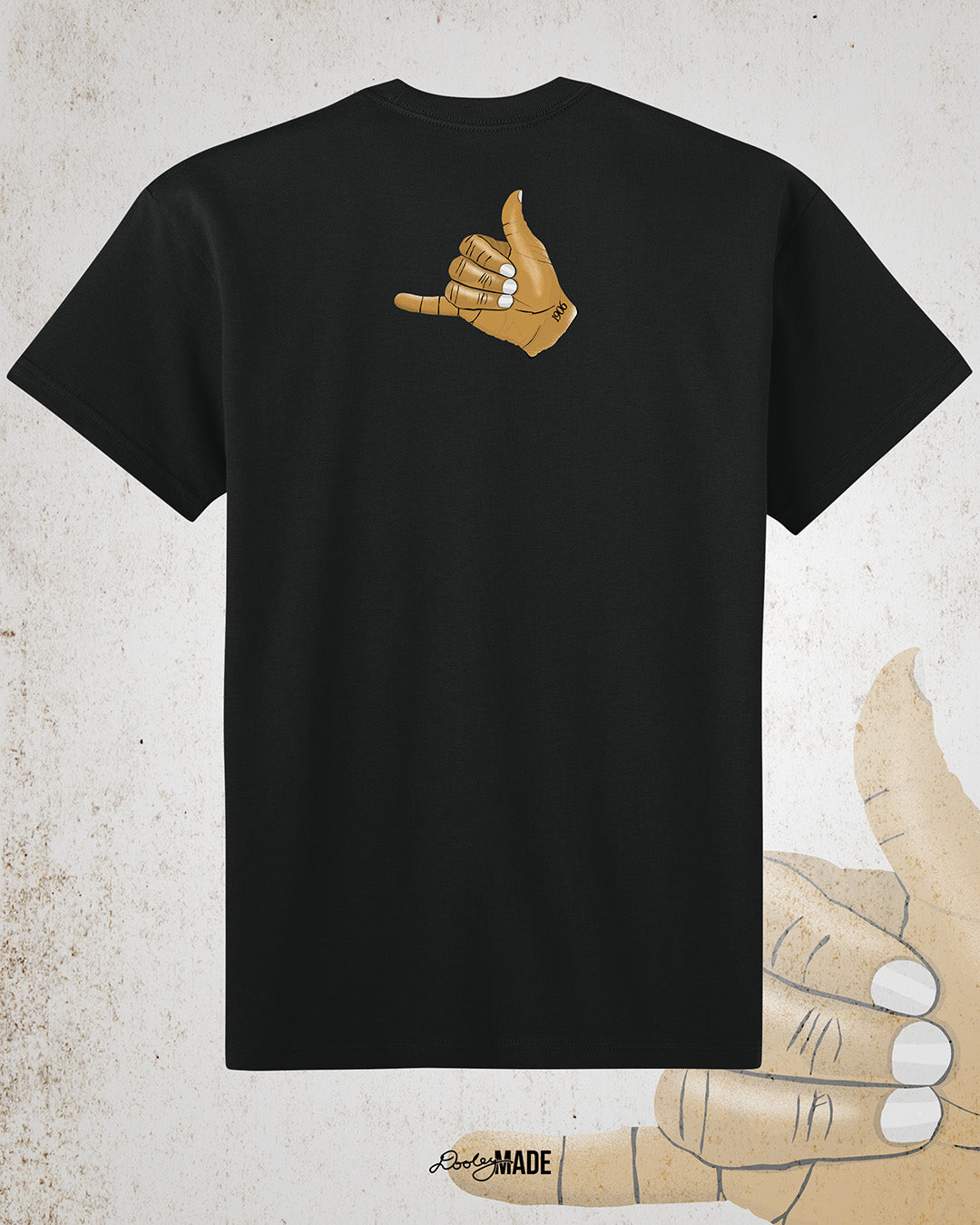 The back of a Black t-shirt with an old gold Alpha Phi Alpha Fraternity, Inc. "ICE" hand sign with "1906" text on the wrist. Image shows the design small on the upper portion of the back.