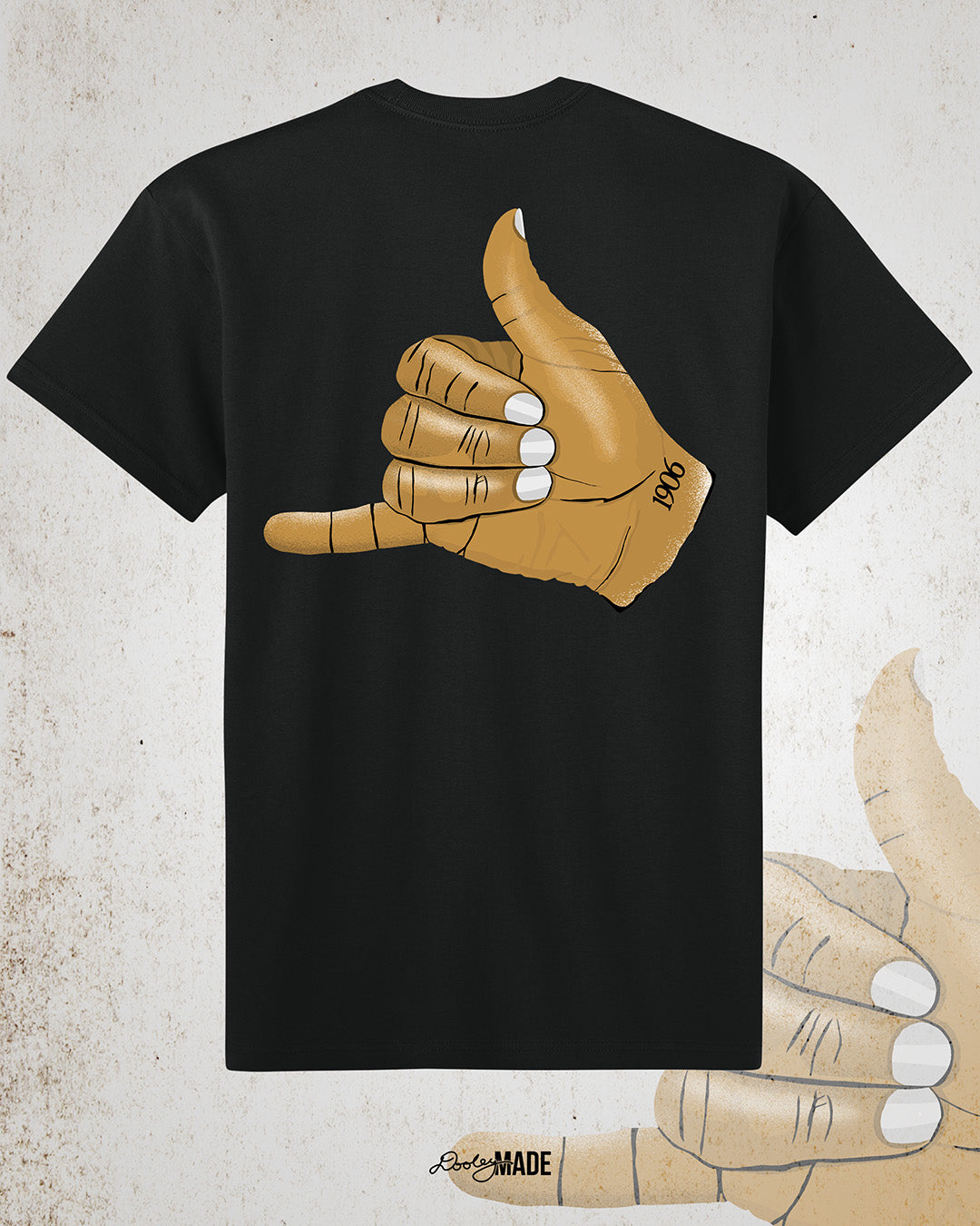The back of a Black t-shirt with an old gold Alpha Phi Alpha Fraternity, Inc. "ICE" hand sign with "1906" text on the wrist. Image shows the design large on the back of the shirt.
