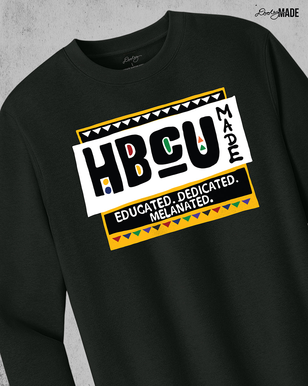 A premium black crewneck sweater featuring a bold HBCU Made 90s Martin Show themed design featuring the text "Educated, Dedicated, Melanated. The design is white, black, yellow, and various other vibrant colors.