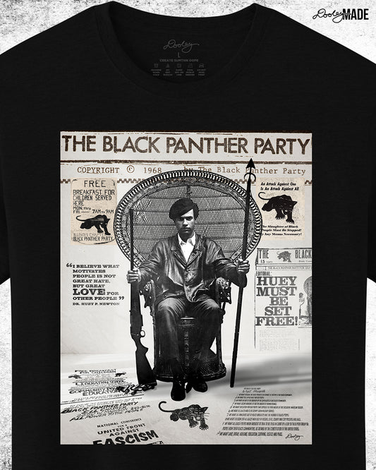 A graphic tee shirt with an image of Huey P. Newton artwork featuring the Black Panther Party's 10 Point Program, a poster that hung inside the door of the Chicago Chapter headquarters, the quote "I believe what motivates people is not great hate, but great love for other people," and other historical memorabilia. Shirt is zoomed in with the sleeve out of frame.