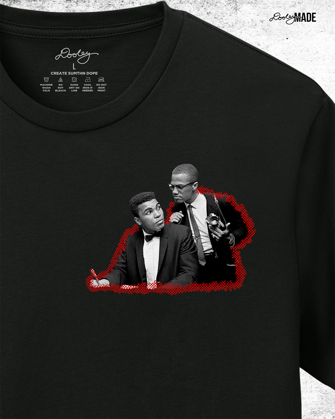 The front of Black t-shirt, zoomed to show detail, featuring a collage of Malcolm X and Muhammad Ali with newspaper headlines and photos, titled 'Malcolm X & Ali: Blood Brothers' in bold red and white text.