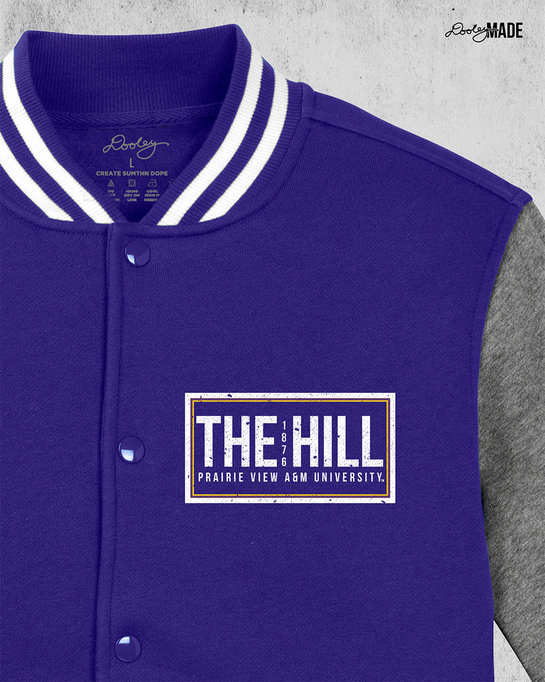 A zoomed in purple and heather gray Prairie View A&M Fleece Varsity Letterman Jacket. The front left chest has 'The Hill' and 'Prairie View A&M University' text printed in white inside of a rectangular box.