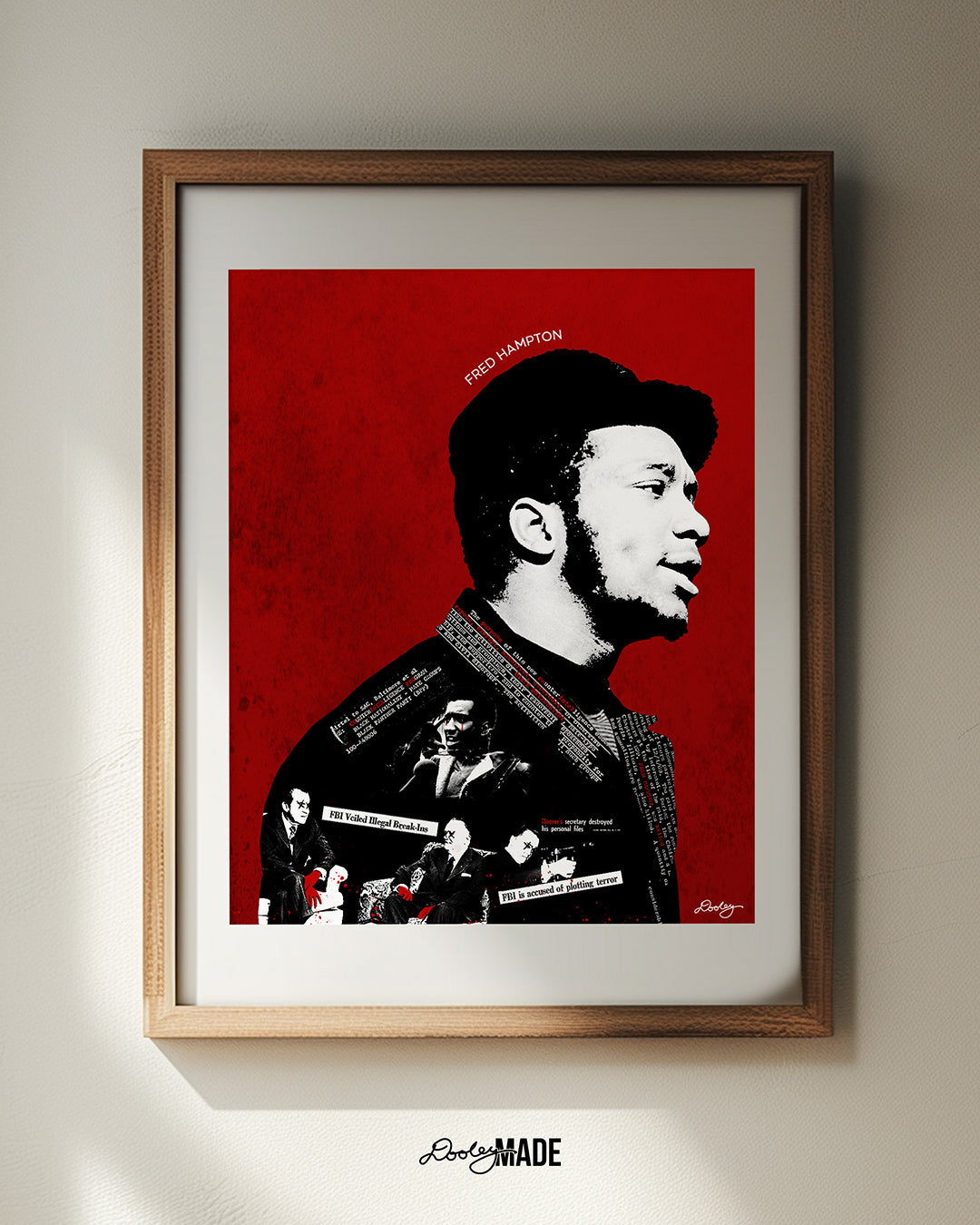 A brown picture frame hug on a white wall featuring a red, black and white Fred Hampton artwork depicting the FBI’s nefarious “Cointel-Pro” program and their pursuit and assassination of Black Political Leaders.