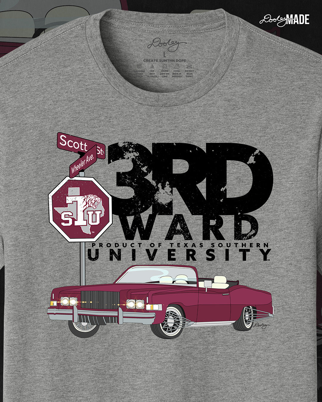 An image of the front of a heather gray Texas Southern University graphic tee shirt featuring a 3rd Ward University design and a maroon old school car with elbow rims. There is also a Scott St and Wheeler Ave street sign with a stop sign with the Texas Southern University logo on it.