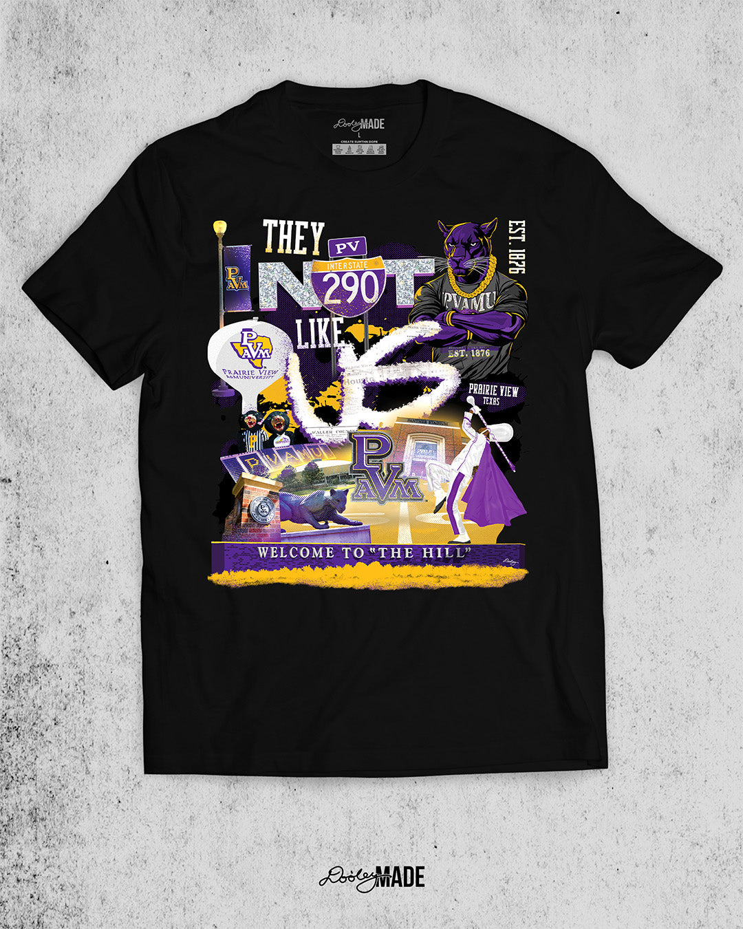 A "They Not Like Us" themed Prairie View A&M black shirt featuring a vibrant collage with a hand drawn elements: a panther panther wearing a gold chain, an interstate 290 sign, the PV water tower, mascots, a marching storm drum major, the panther statue and the "Welcome to the Hill" sign.