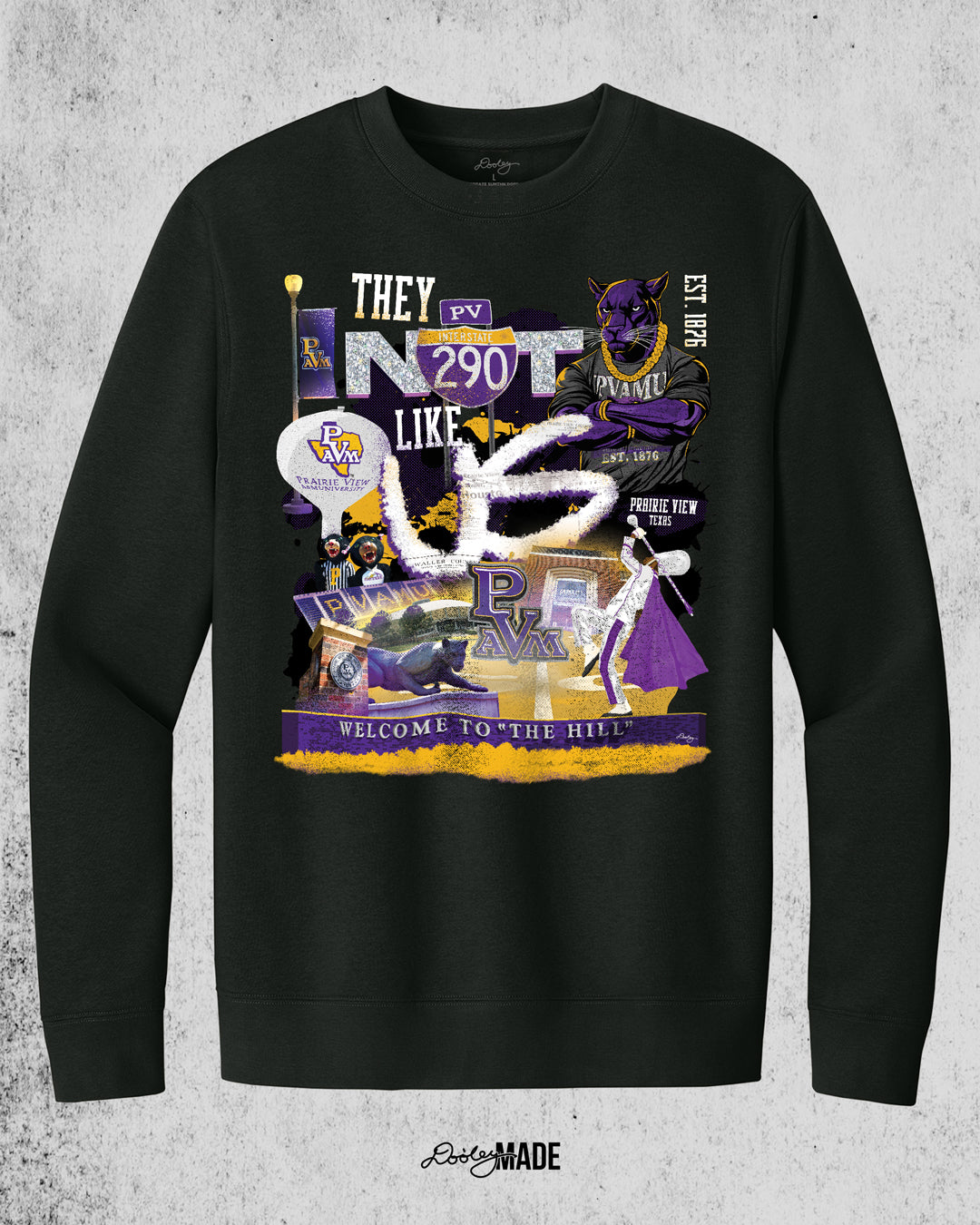 A "They Not Like Us" themed Prairie View A&M black crewneck sweater featuring a vibrant collage with a hand drawn elements: a panther panther wearing a gold chain, an interstate 290 sign, the PV water tower, mascots, a marching storm drum major, the panther statue and the "Welcome to the Hill" sign.