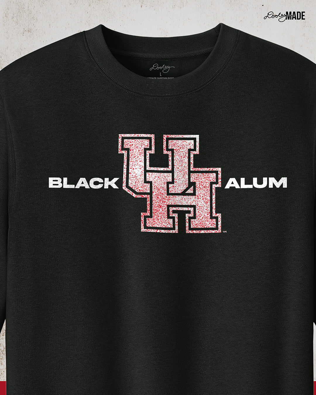 Image of a black "Black UH Alumni crewneck sweater" showcasing bold, white text reading "BLACK ALUM" flanking a speckled white and red "UH" logo in the center. The design emphasizes pride and unity for Black alumni of the University of Houston, presented on a stylish and modern garment ideal for representing school spirit and Cougar pride.