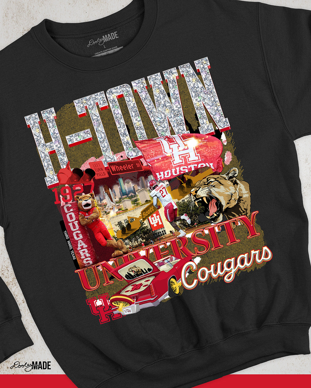 A black University of Houston themed crewneck sweater featuring a vibrant HTOWN University graphic collage with "H-TOWN" text in diamonds, Cougar mascot, players, city skyline, and classic lowrider in a vibrant collage design.