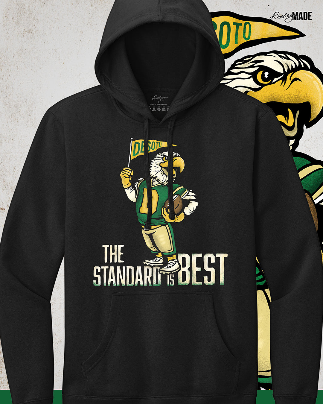Vintage black hoodie sweatshirt featuring a retro-inspired eagle mascot holding a football and waving a "DeSoto" Pennant flag. Bold text reads "The Standard is Best," accented with green and gold colors, celebrating DeSoto High School pride and tradition.