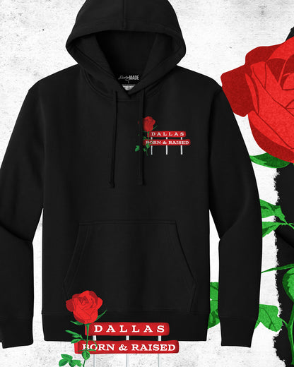 An image of heavyweight black hoodie from The Dallas Concrete Rose Collection featuring a vibrant illustration by Dre Dooley of a Rose and a sign "Dallas Born and Raised" on the left chest. 