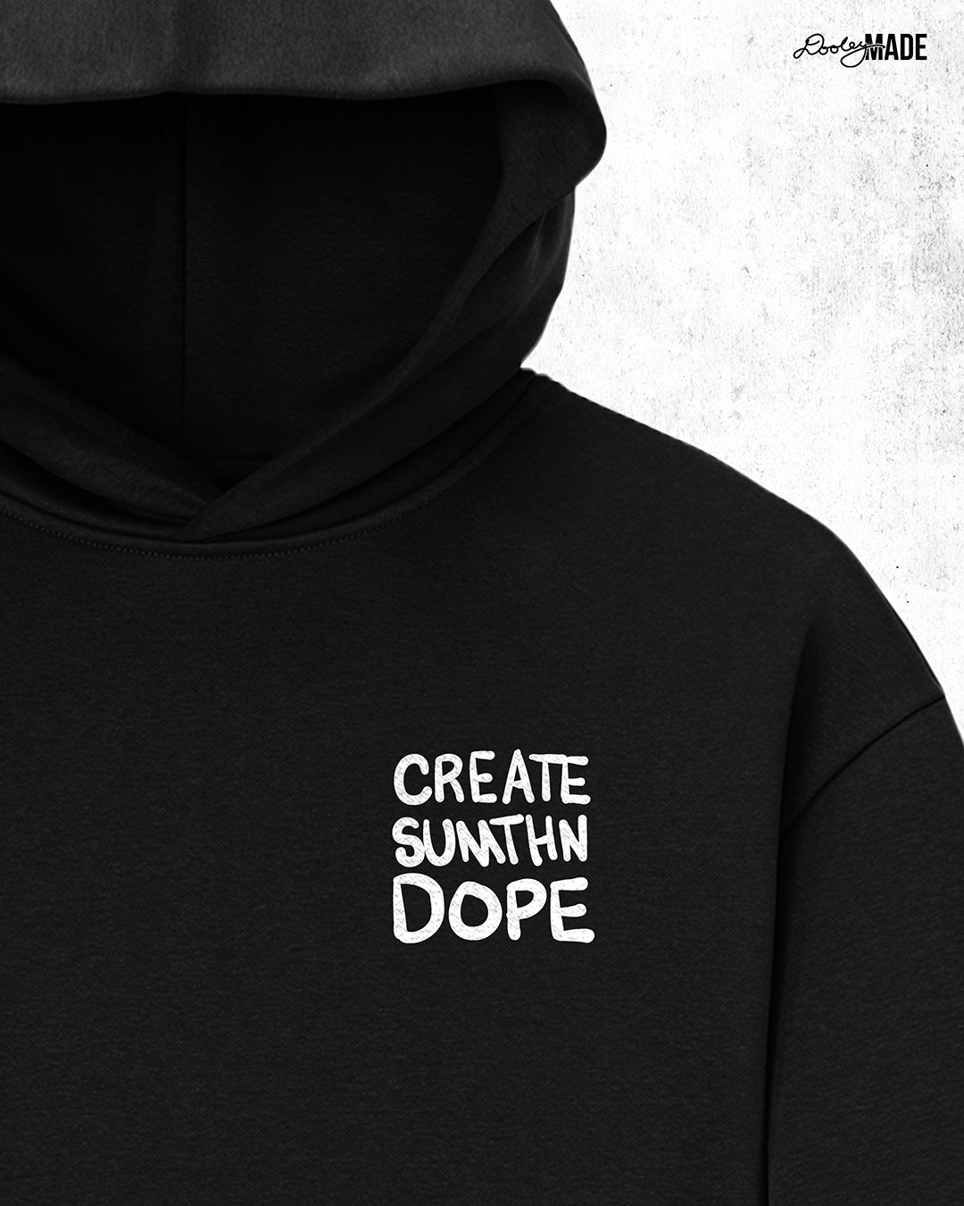A heavy oversized Black hoodie with white 'CREATE SUMTHN DOPE' text on left chest, displayed against a textured white background. Created by Dooley Made.