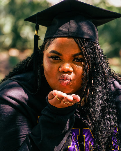 A warm photo advertising Personalized Graduation Photography showing a graduate wearing a graduation cap while blowing a kiss at the camera with a hand outstretched. 