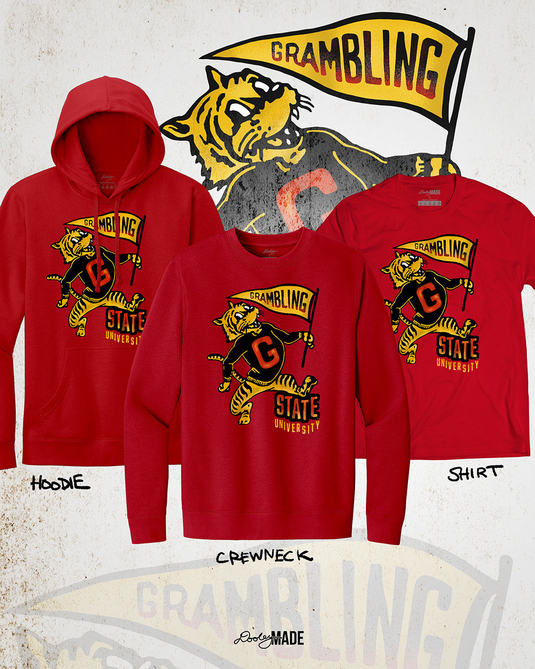 This is an image of a premium red hoodie, crewneck sweater, and shirt featuring a retro-style design celebrating Grambling State University. The design includes a vintage illustration of a tiger mascot holding a yellow pennant that reads "Grambling" in bold letters. The tiger wears a shirt with a large red "G." Under the tiger is the text "State University" in red and yellow, giving it a distressed, classic look. The background features a faint overlay of the same tiger mascot design for added texture. 