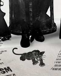 An zoomed image of Huey P. Newton artwork showing his feet and the Black Panther Party's illustrated panther logo icon stretched on the floor. 