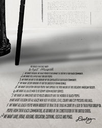 A zoomed image of Huey P. Newton artwork featuring the Black Panther Party's 10 Point Program outstretched in perspective on the floor. 