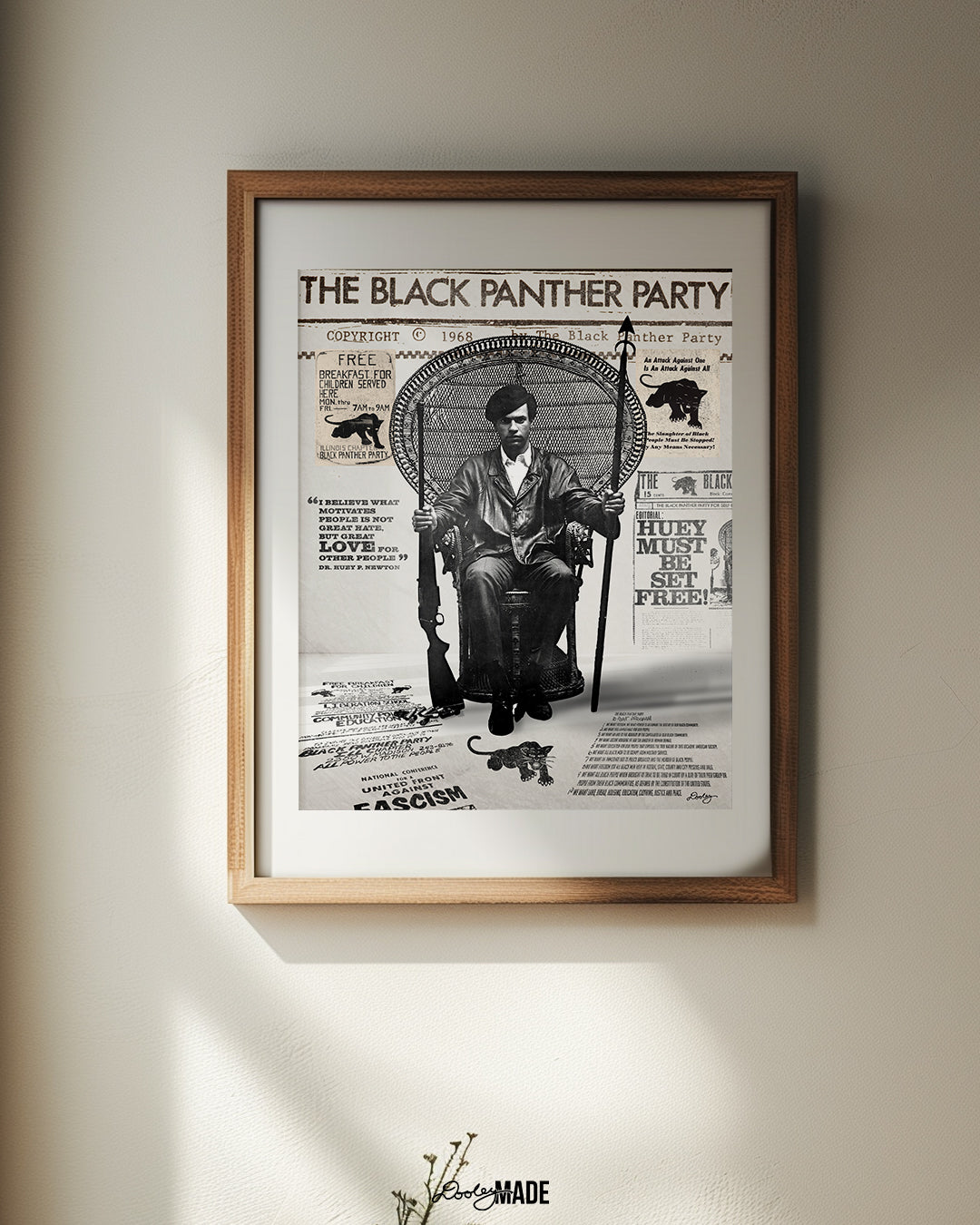 An image of framed Huey P. Newton artwork featuring the Black Panther Party's 10 Point Program, a poster that hung inside the door of the Chicago Chapter headquarters, the quote "I believe what motivates people is not great hate, but great love for other people," and other historical memorabilia. The frame is on a eggshell wall next to a window.