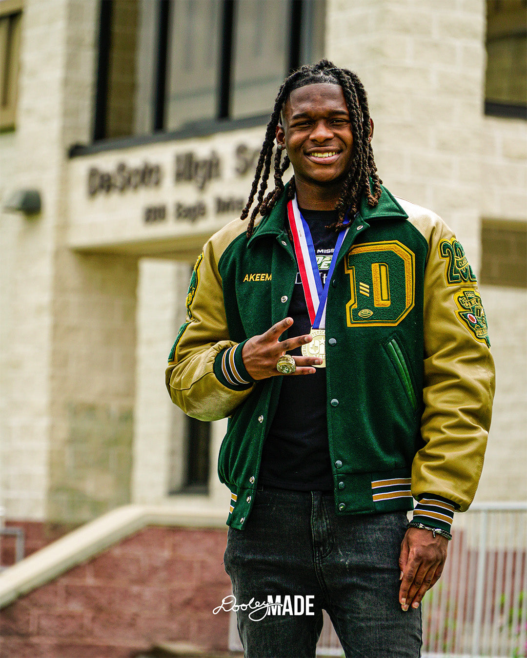 A photo advertising Personalized Graduation Photography showing a graduate smiling and standing in front of a high school wearing a green letterman jacket and state UIL medal.