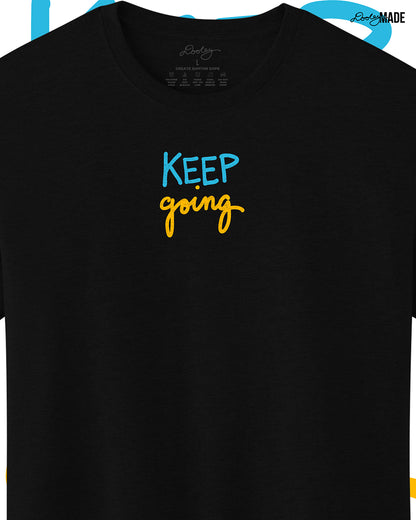 Heavyweight Black t-shirt with 'KEEP going' text in blue and yellow on a white background, slightly zoomed to show detail.