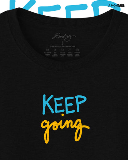 Heavyweight Black t-shirt with 'KEEP going' text in blue and yellow on a white background, zoomed to show detail.