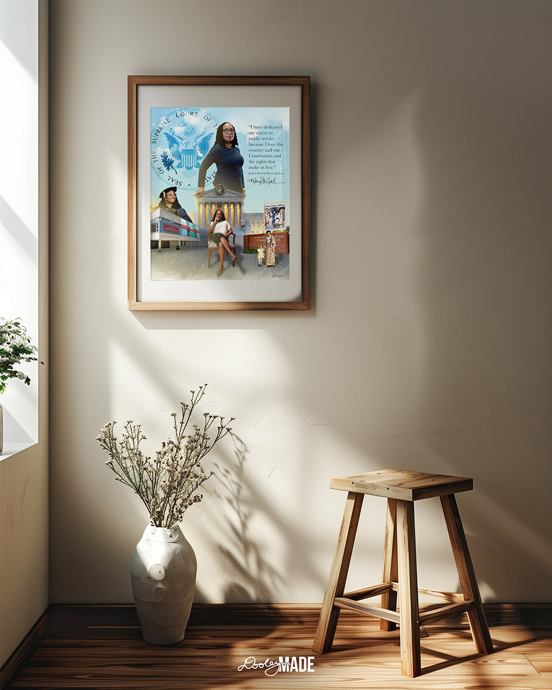An image of a wooden picture frame on a white wall next to a window thats casting light upon a digital collage honoring Justice Ketanji Brown Jackson. It showcases key moments from her life and career. The central figure is a confident Justice Jackson standing in front of the Supreme Court seal. To the left, she is depicted at her Harvard Law School graduation, with the school's building in the background. 