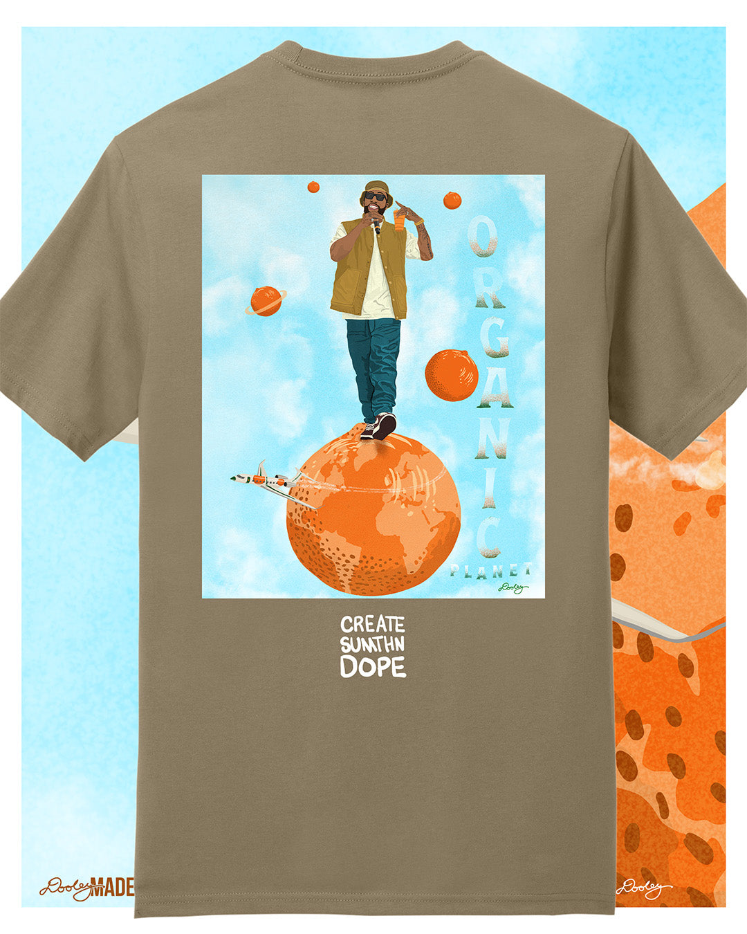 A khaki tan Larry June themed graphic t-shirt featuring a Larry June illustration of him standing on an orange planet with floating orange planets, alongside the text "Organic Planet" and "Create Sumthin Dope." Bold streetwear design blending creativity, luxury, and hip-hop culture.