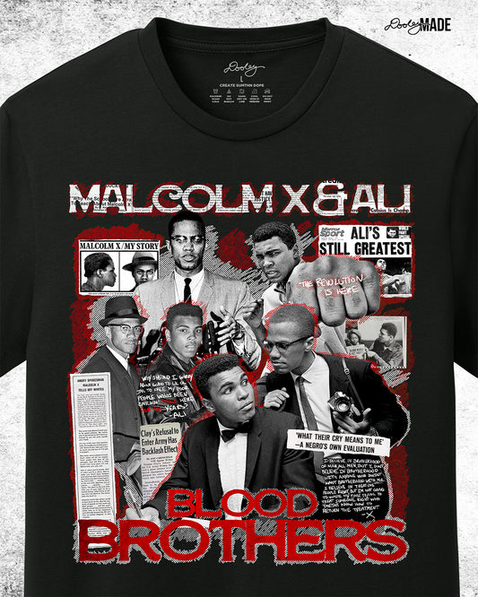 The front of a Black t-shirt featuring a collage of Malcolm X and Muhammad Ali with newspaper headlines and photos, titled 'Malcolm X & Ali: Blood Brothers' in bold red and white text.