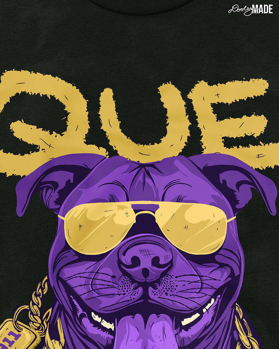 A photo showing the detail of the top of a black shirt with a graphic of an Omega Psi Phi Fraternity, Inc themed Pit Bull Dog wearing gold aviator sunglasses and a gold Omega Psi Phi necklace.
