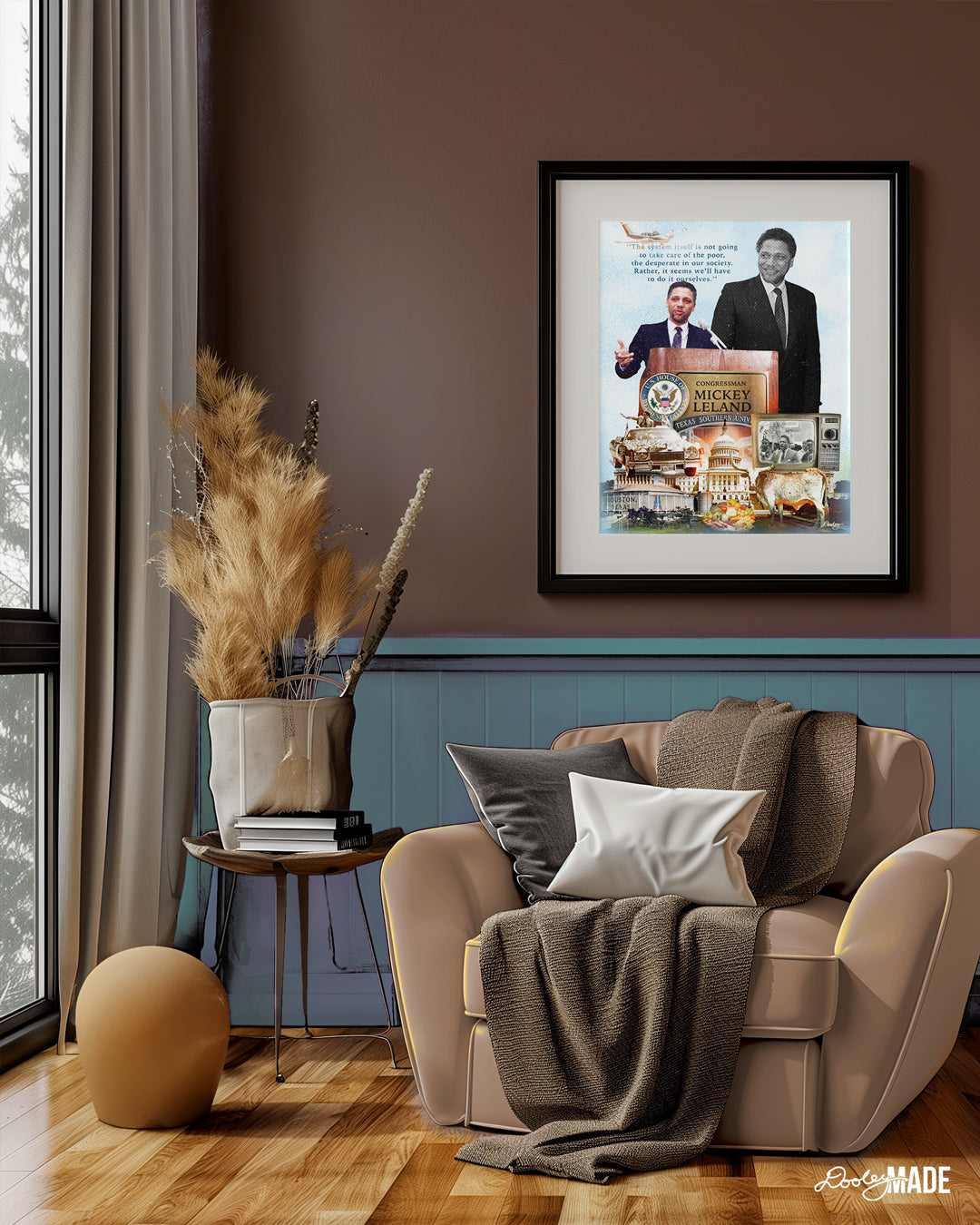 The image depicts a tastefully decorated room. There is a large framed Congressman Mickey Leland Collage artwork hanging on a deep brown wall. Collage featuring Congressman Mickey Leland speaking at a podium, with quotes and images of the U.S. Capitol, Texas Southern University, The Houston Astrodome, a vintage TV, a longhorn, him riding a car in a parade, and fruits and vegetables. The room is furnished with a comfortable armchair, a side table holding books, and a decorative vase with dried flowers. Large