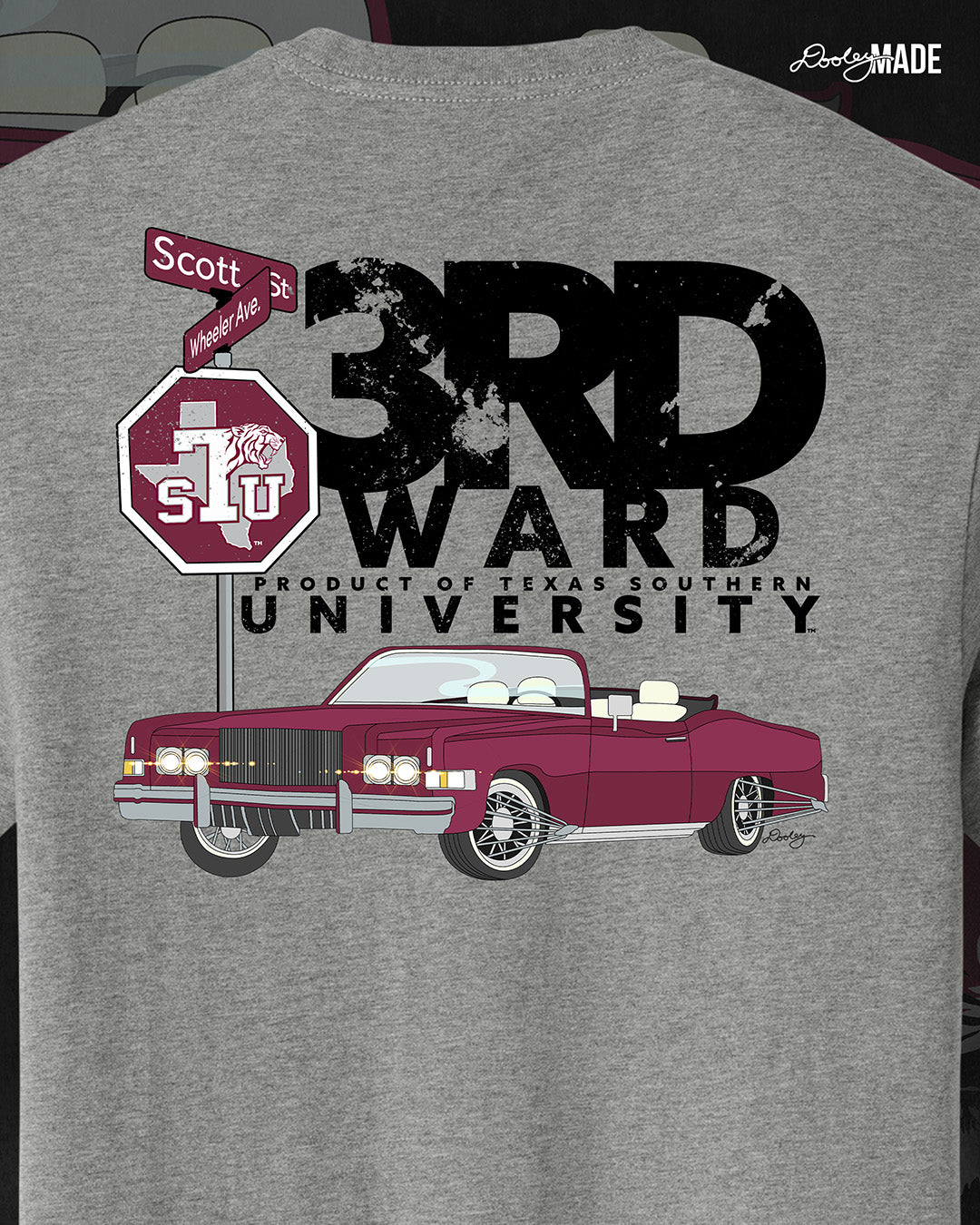 An image of the back of a heather gray Texas Southern University graphic tee shirt featuring a 3rd Ward University design and a maroon old school car with elbow rims. There is also a Scott St and Wheeler Ave street sign with a stop sign with the Texas Southern University logo on it. 