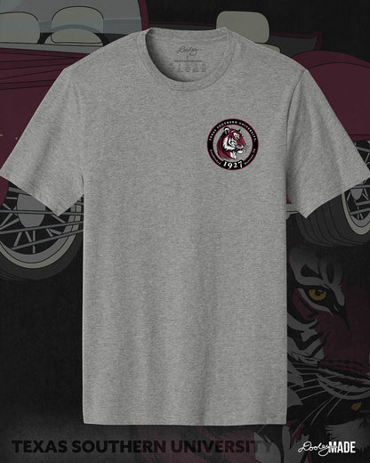 An image of the front of a heather gray Texas Southern University graphic tee shirt featuring a 3rd Ward University design and a maroon old school car with elbow rims. There is also a Scott St and Wheeler Ave street sign with a stop sign with the Texas Southern University logo on it. The front shows a circular print with the words Texas Southern University Established 1927 Houston, Tx  around the border with a stylized tiger inside of it. 