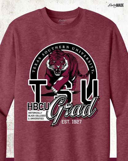 A heather maroon Texas Southern University graduation crewneck sweater featuring a prowling tiger surrounded by a circular frame with the university name inside of it, and the words "TSU Grad" next to HBCU and Historically Black Colleges & University, zoomed to show details. 