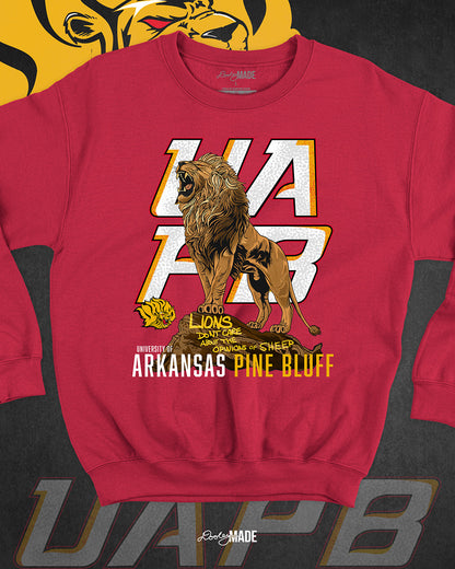 The front of a red University of Arkansas Pine Bluff graphic crewneck sweater with the slogan "Lions Don't Care About The Opinions of Sheep" on the front with a Lion roaring on top of a rock in front of a stylized UAPB logo.