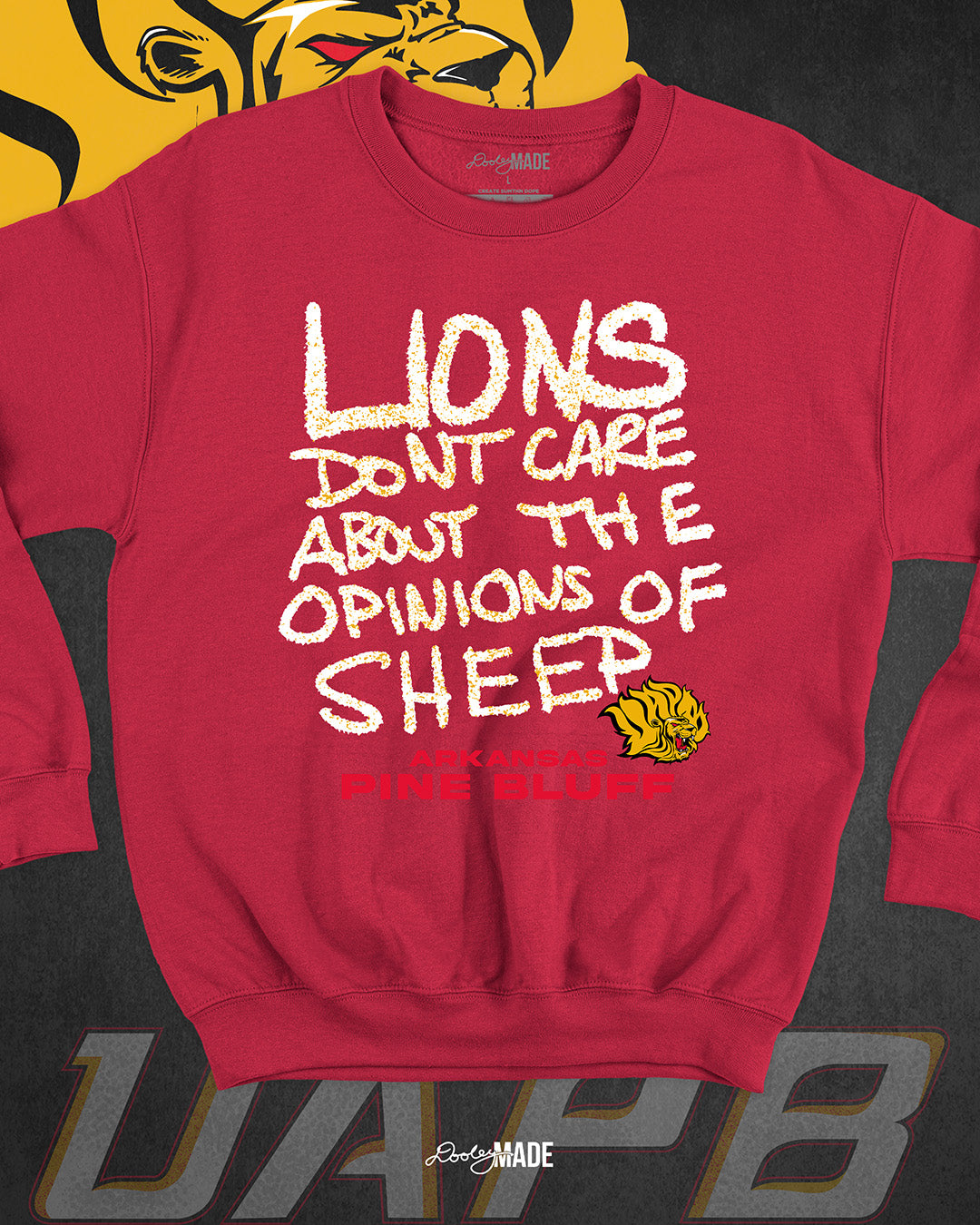 The front of a red University of Arkansas Pine Bluff graphic crewneck sweater with the slogan "Lions Don't Care About The Opinions of Sheep" on the front and the UAPB lion logo.