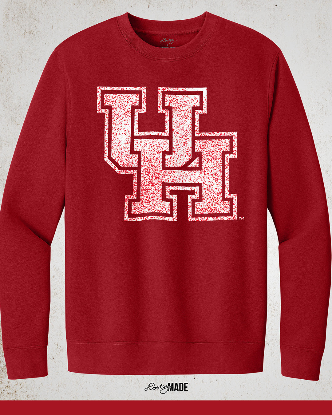 Image showing a red University of Houston crewneck sweatshirt with a white UH logo with red speckles stretched across the front.