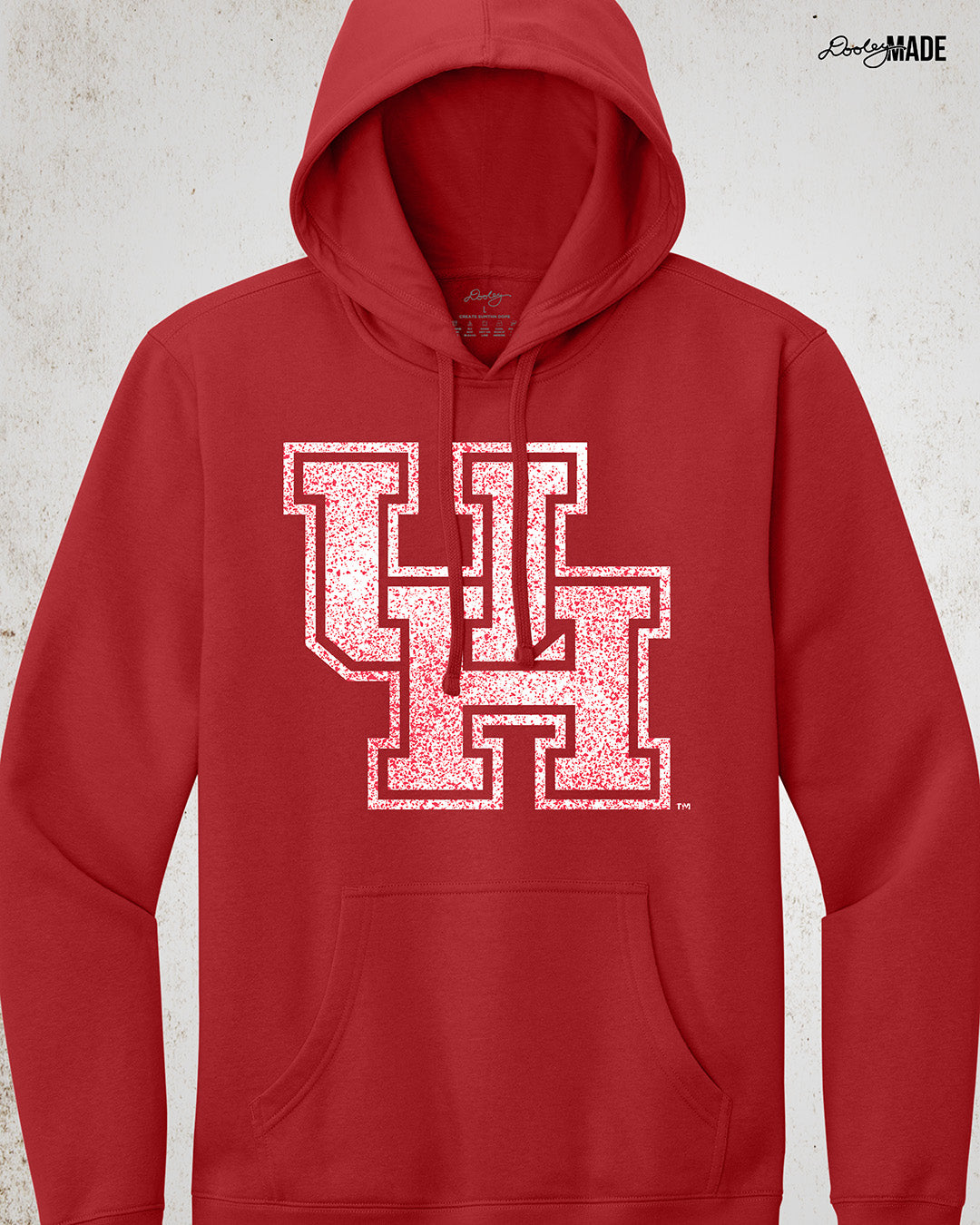 Image showing a red University of Houston hoodie  with a white UH logo with red speckles stretched across the front.