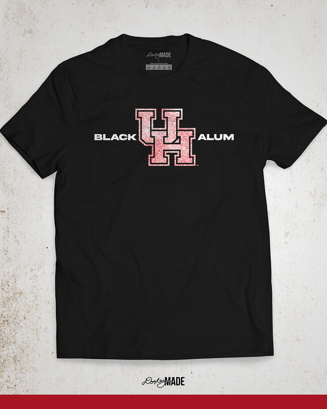 Image of a black "Black UH Alumni Shirt" showcasing bold, white text reading "BLACK ALUM" flanking a speckled white and red "UH" logo in the center. The design emphasizes pride and unity for Black alumni of the University of Houston, presented on a stylish and modern garment ideal for representing school spirit and Cougar pride.