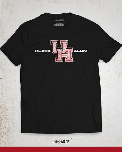 Image of a black "Black UH Alumni Shirt" showcasing bold, white text reading "BLACK ALUM" flanking a speckled white and red "UH" logo in the center. The design emphasizes pride and unity for Black alumni of the University of Houston, presented on a stylish and modern garment ideal for representing school spirit and Cougar pride.