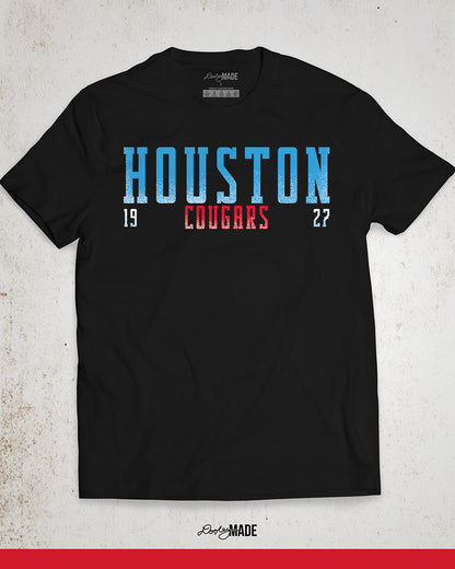 A black University of Houston Cougars themed shirt with "Houston" written in Oiler Blue block text. The text "Cougars" is below in white and 1927 is split below in white. The text contains a white grunge texture on its lower half. Perfect for alumni, students, and fans.