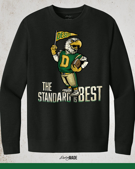 Vintage black crewneck sweatshirt featuring a retro-inspired eagle mascot holding a football and waving a "DeSoto" Pennant flag. Bold text reads "The Standard is Best," accented with green and gold colors, celebrating DeSoto High School pride and tradition.